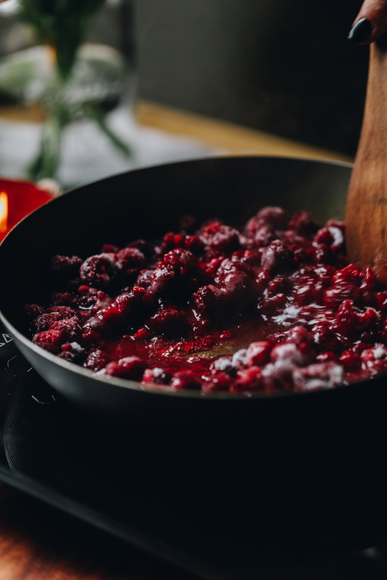 Chia raspberry and lemon jam is cooking over a black portable stove in a frying pan.