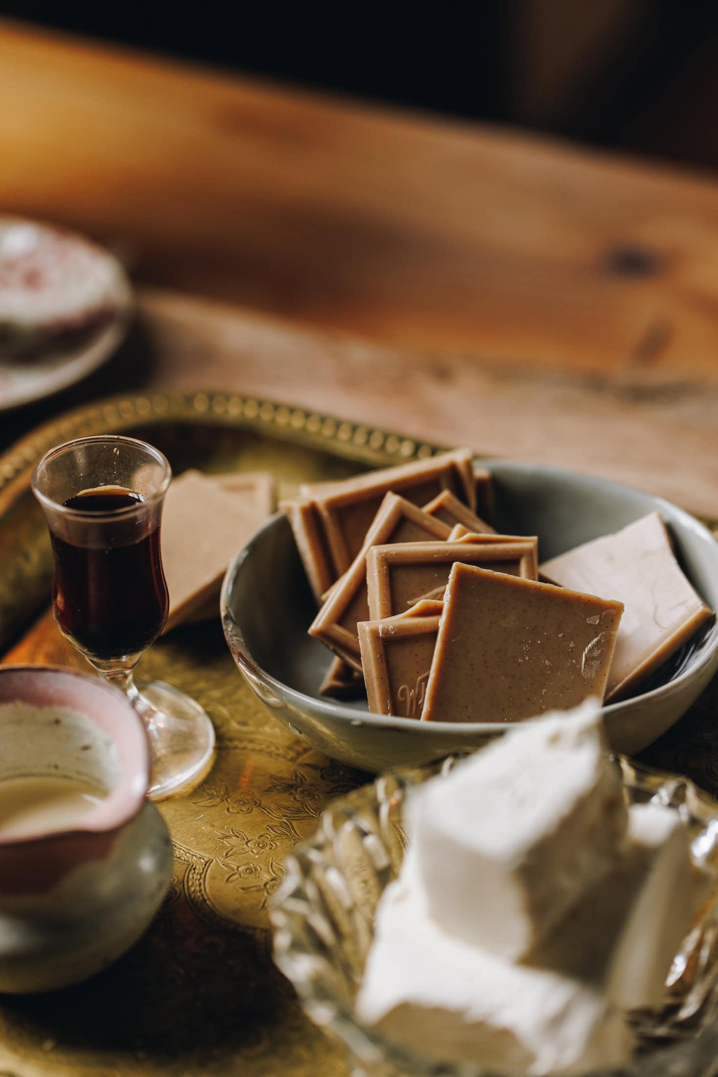 Ingredients are in different vintage bowls and are sitting on a wooden board on top of wooden table. Caramelised white chocolate and vanilla are in focus.