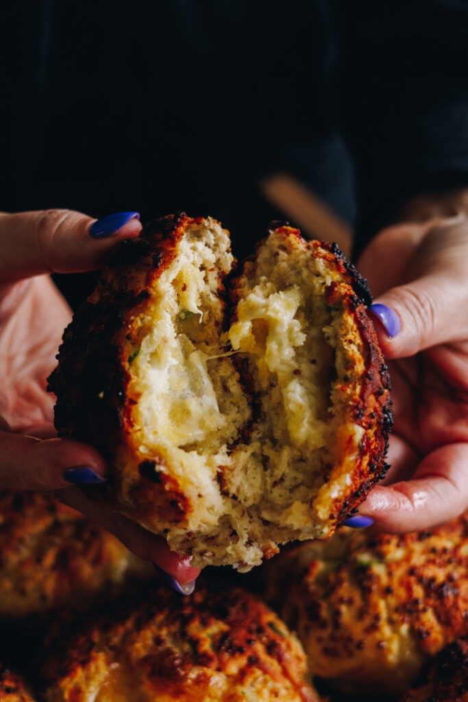 A close up of a Brie Stuffed Honey Mustard Scone is opened up to reveal a gooey brie centre.