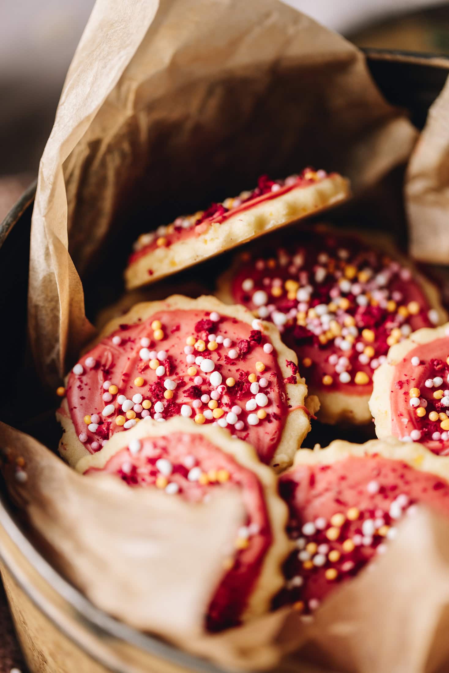 A close up pile of hundreds and thousands biscuits baked and decorated sitting in a biscuit tin.