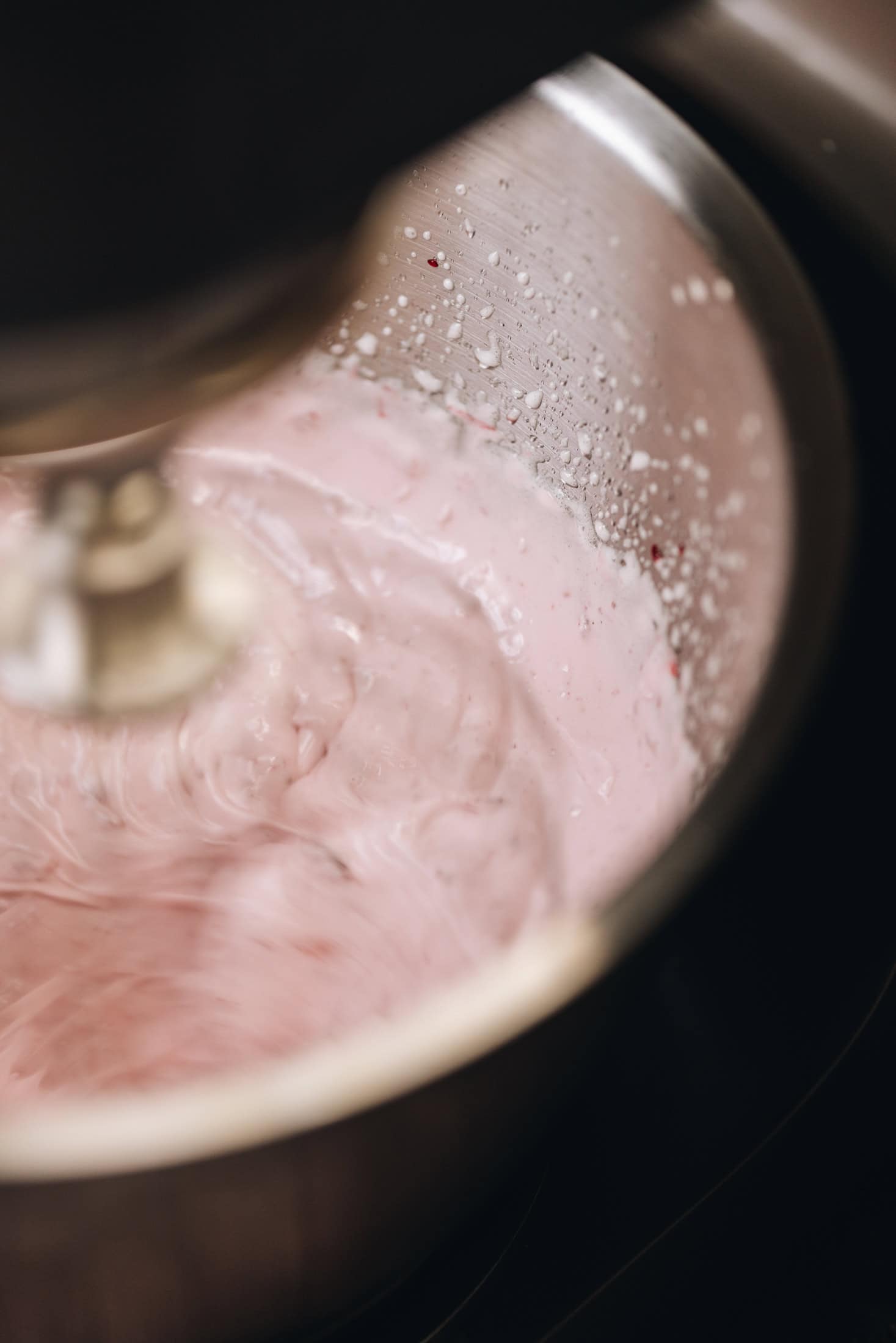 In a silver bowl, in a stand mixture a balloon whisk is whipping the fluffy raspberry marshmallow.