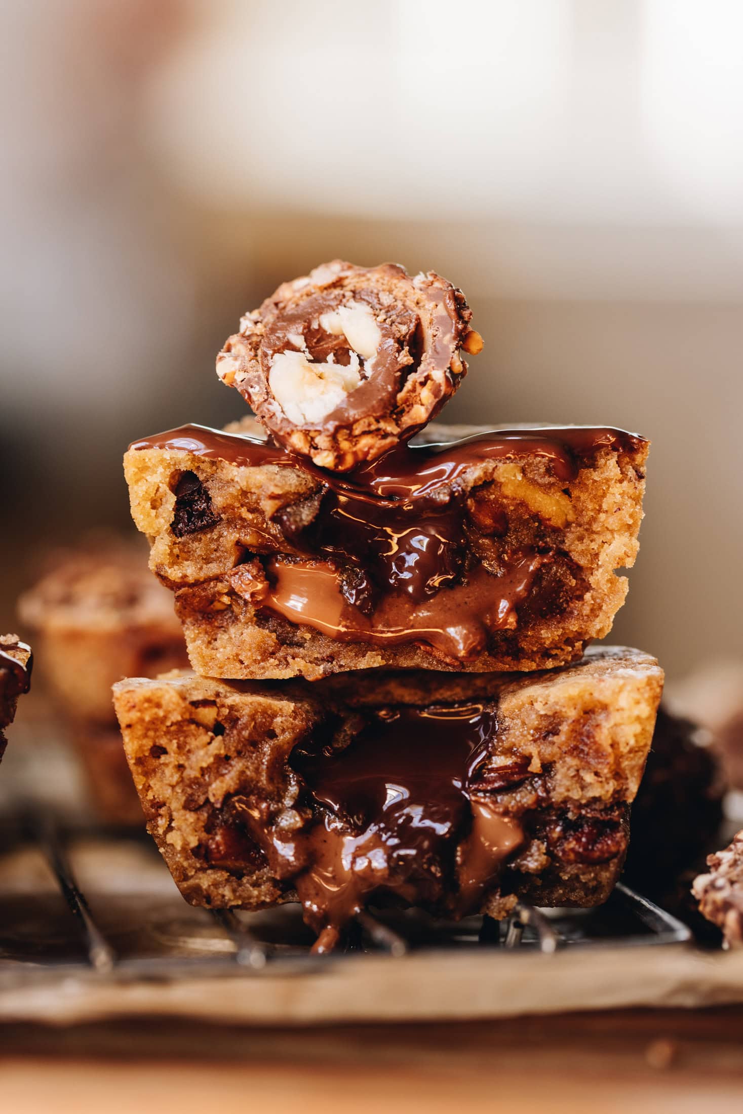 Stacked gooey cookie pies sliced open to reveal a melted chocolate centre oozing out, topped with half a Ferrero Rocher chocolate.