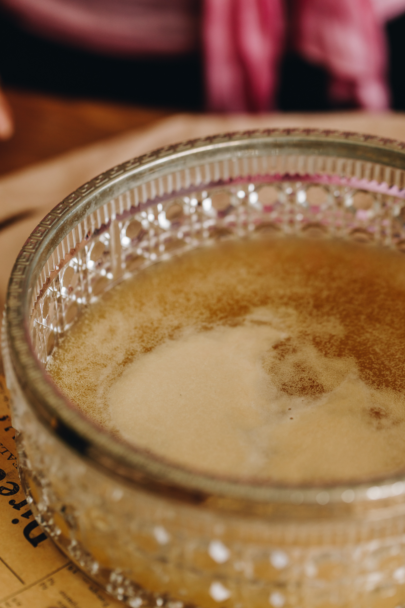 Activated yeast is foamy in a vintage glass bowl with a silver trim. 