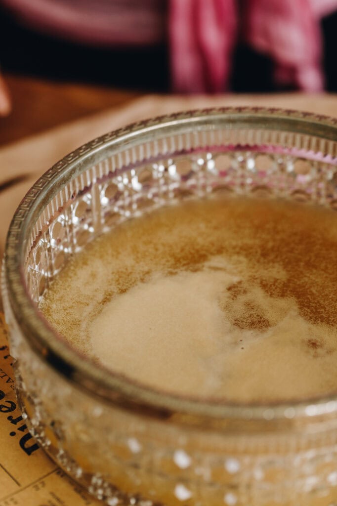 A close up shot of activated yeast that has risen to the top of the water it is sitting in. It sits in a glass bowl with silver trim around the edge.