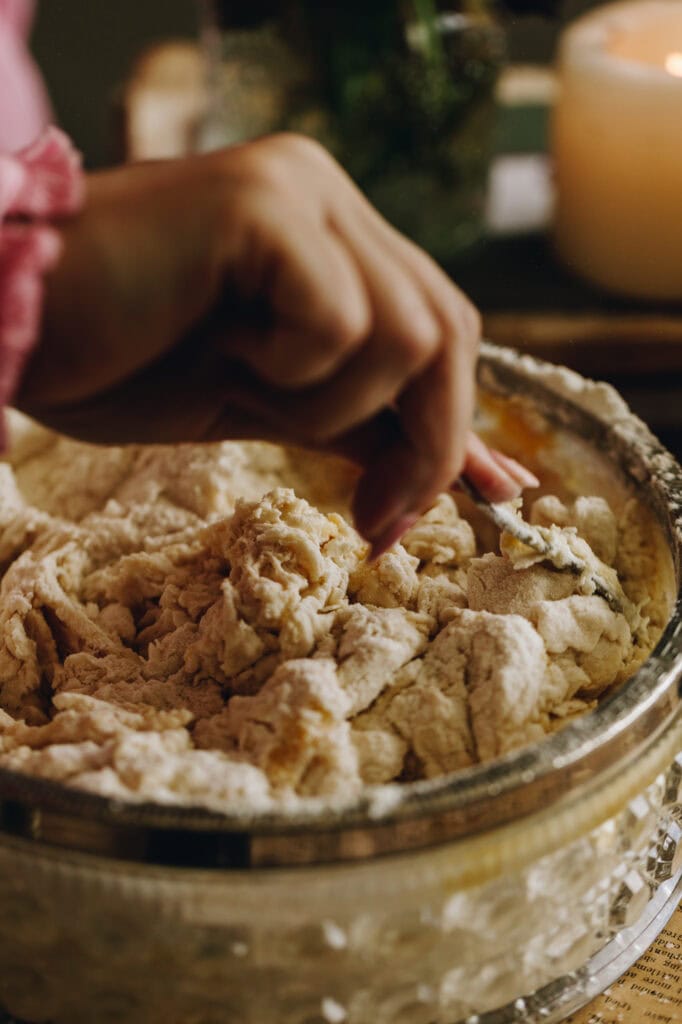 A close up shot of the wet and dry ingredients being mixed together with a fork in a glass bowl with a silver trim around the edge.
