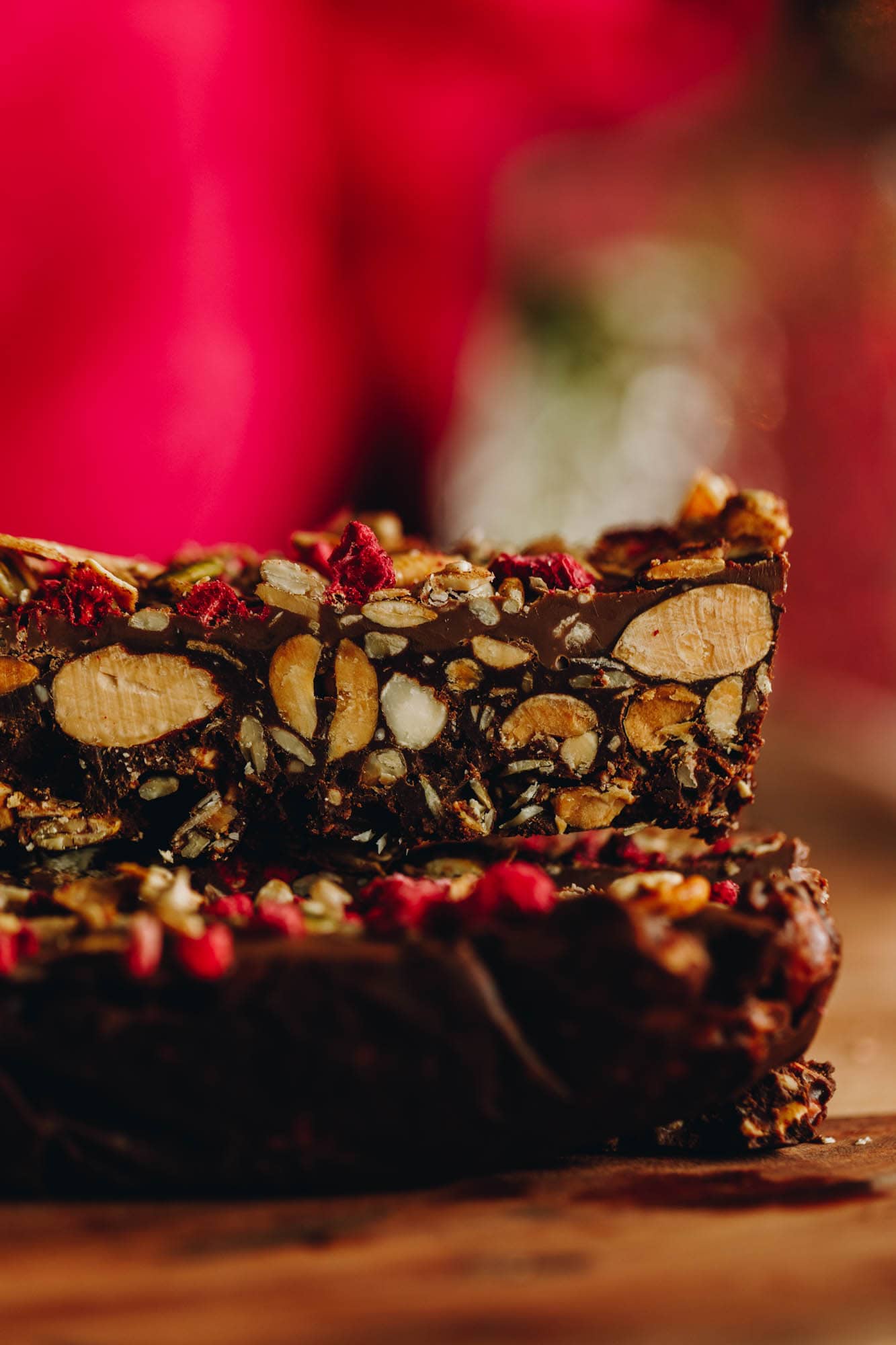 A close up of a slice of chocolate nut and seed slice. The texture shows all the nuts inside the bar.
