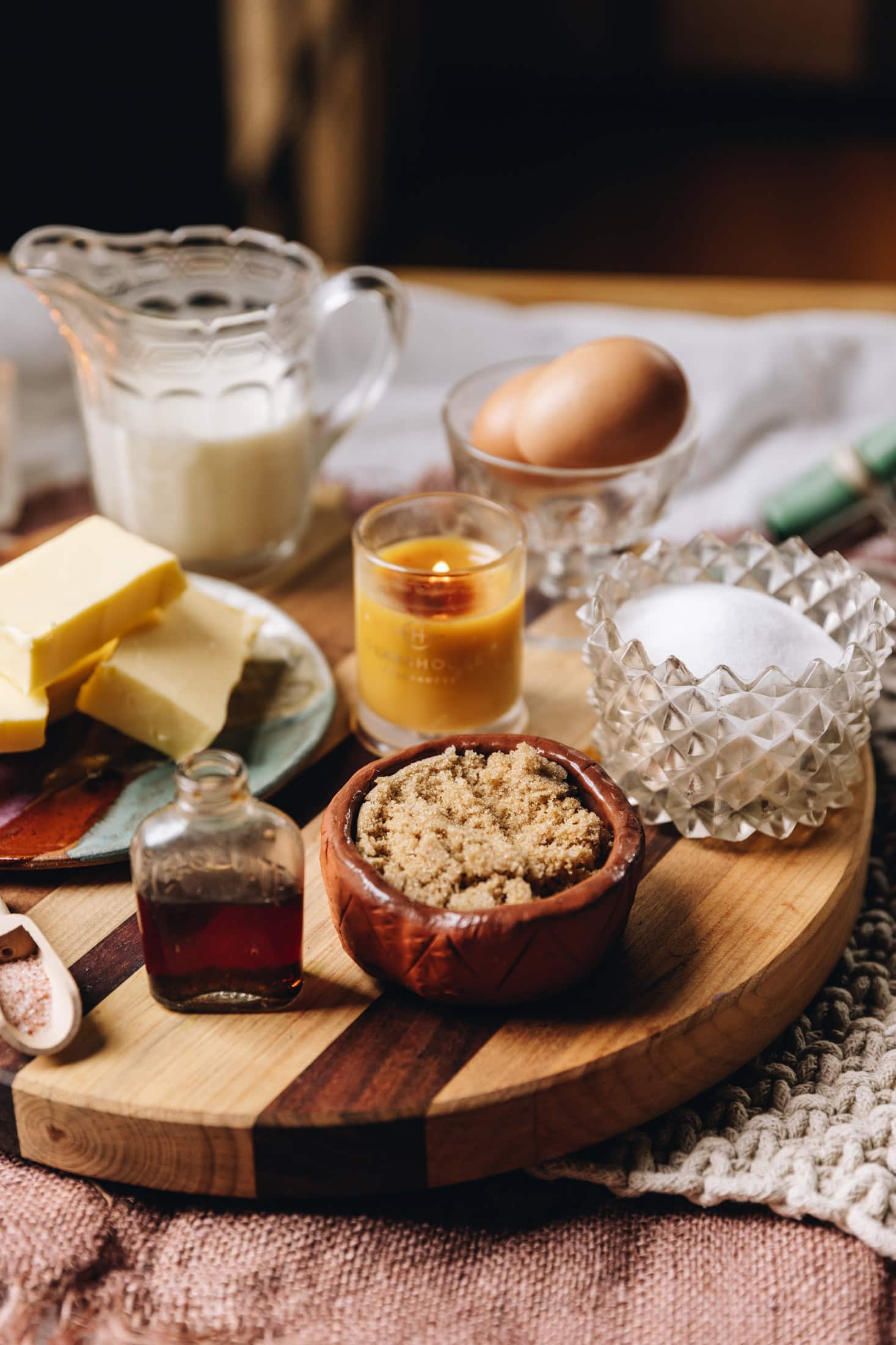 Brown butter vanilla cupcake ingredients are laid out on vintage cups, bowls and cups on a wooden board.