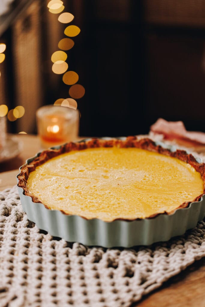Sitting on a weaved cloth is a blue quiche tin with crumpled edges. In it is the baked lemon custard from the Homemade Lemon Meringue Pie. 