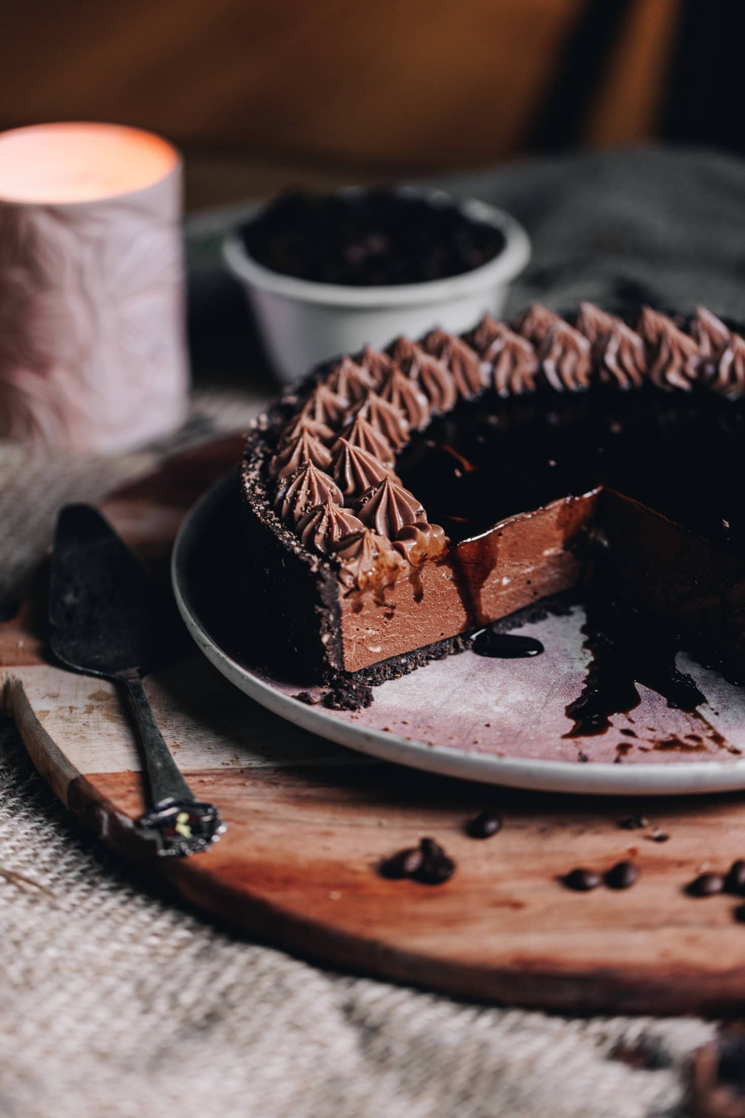 The chilled Mocha cheesecake has been cut open to reveal the filling. It is on a pink plate that is on a wooden board. The coffee syrup is dripping down on to the plate. 