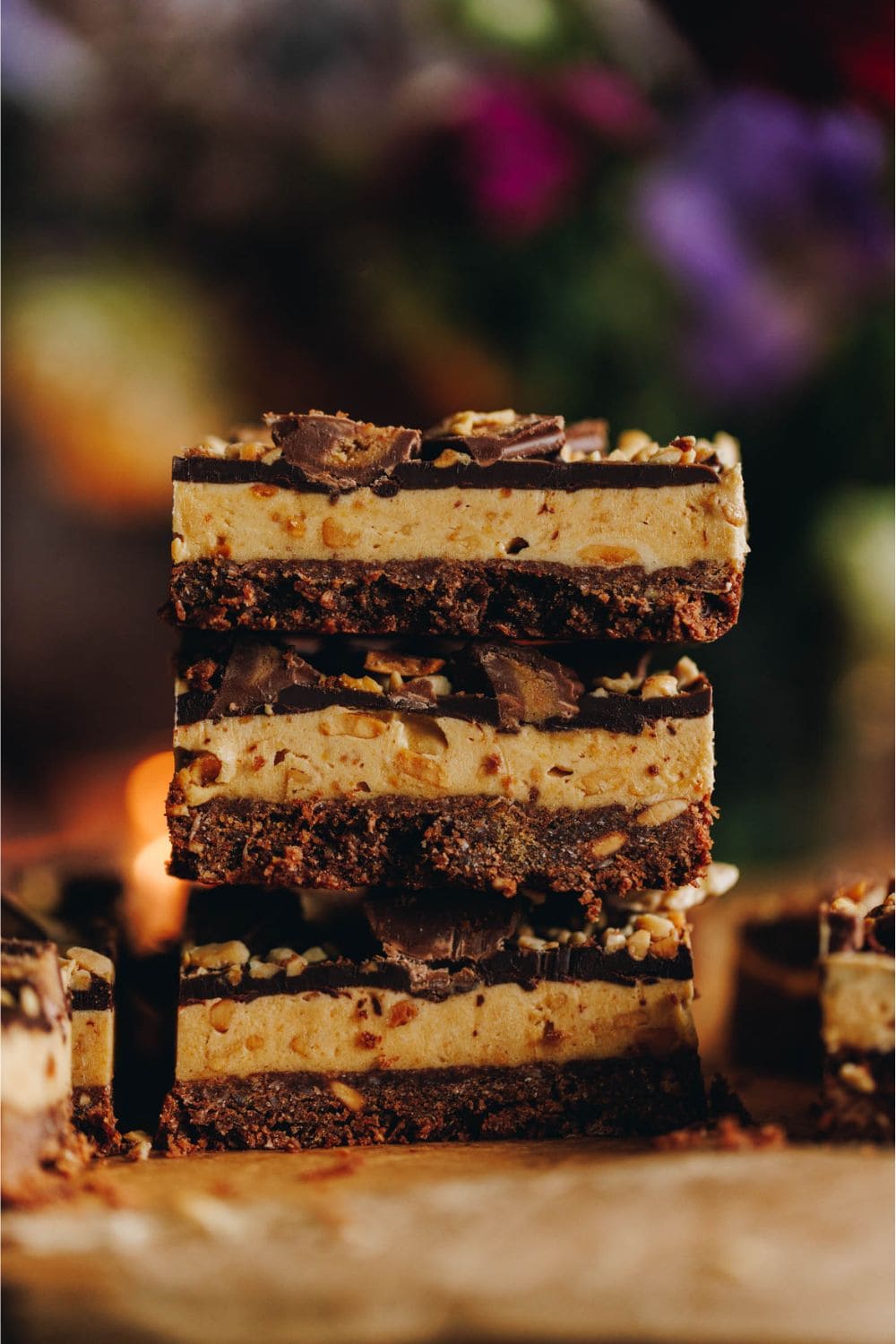 A close up of a stack of three pieces of Peanut Butter Weetbix Slice that is sitting on brown baking paper. 