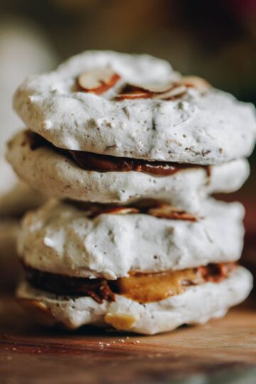 Gluten-free forgotten cookies on a wooden board with one broken open showing the crunchy interior.