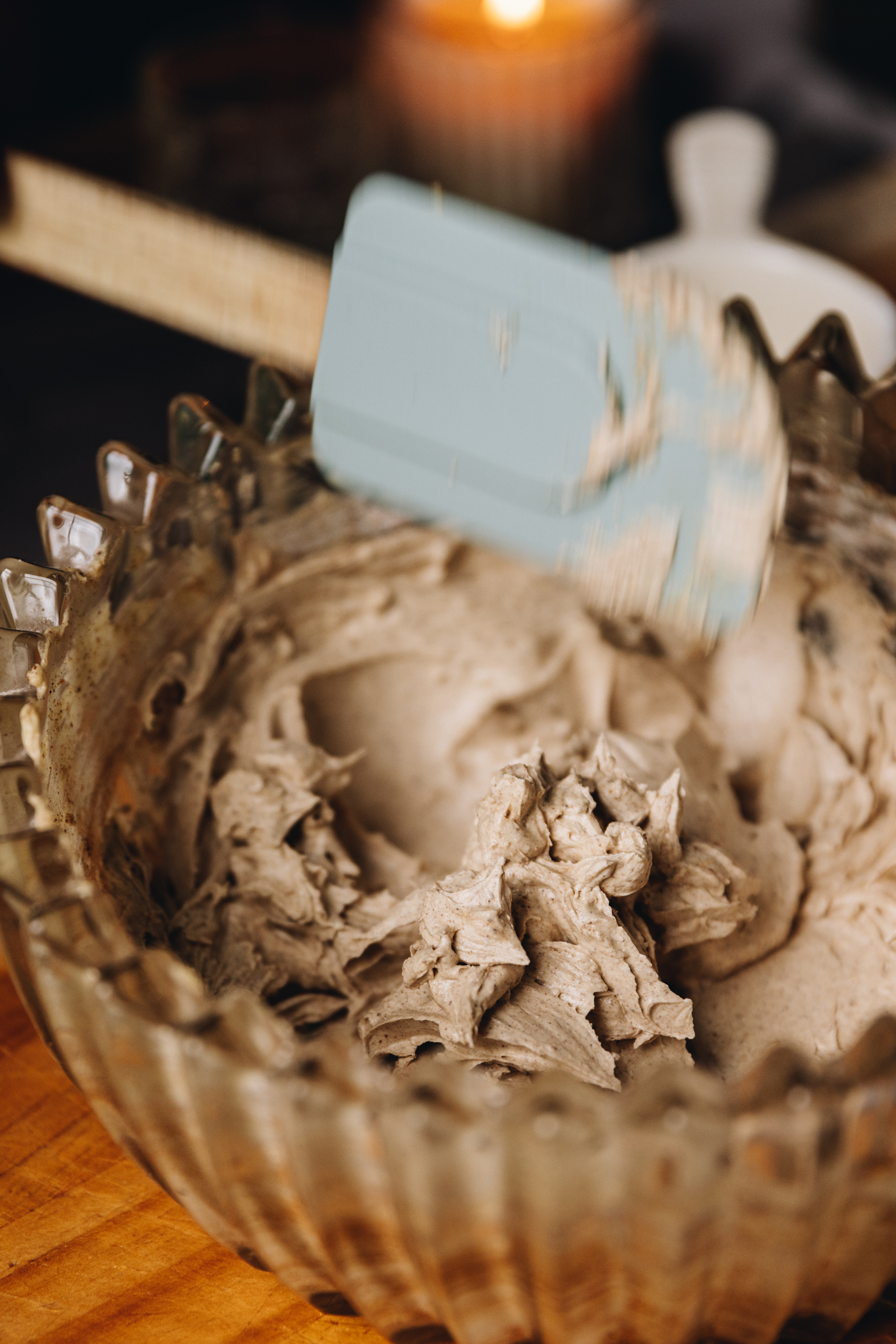 Whipped brown butter buttercream in a glass vintage bowl, on a wooden table.