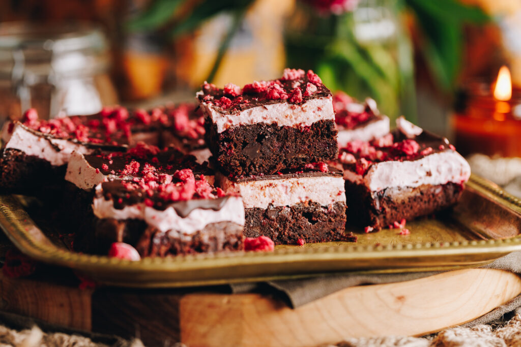 Chocolate raspberry brownie with marshmallow pieces, stacked on a gold tray.