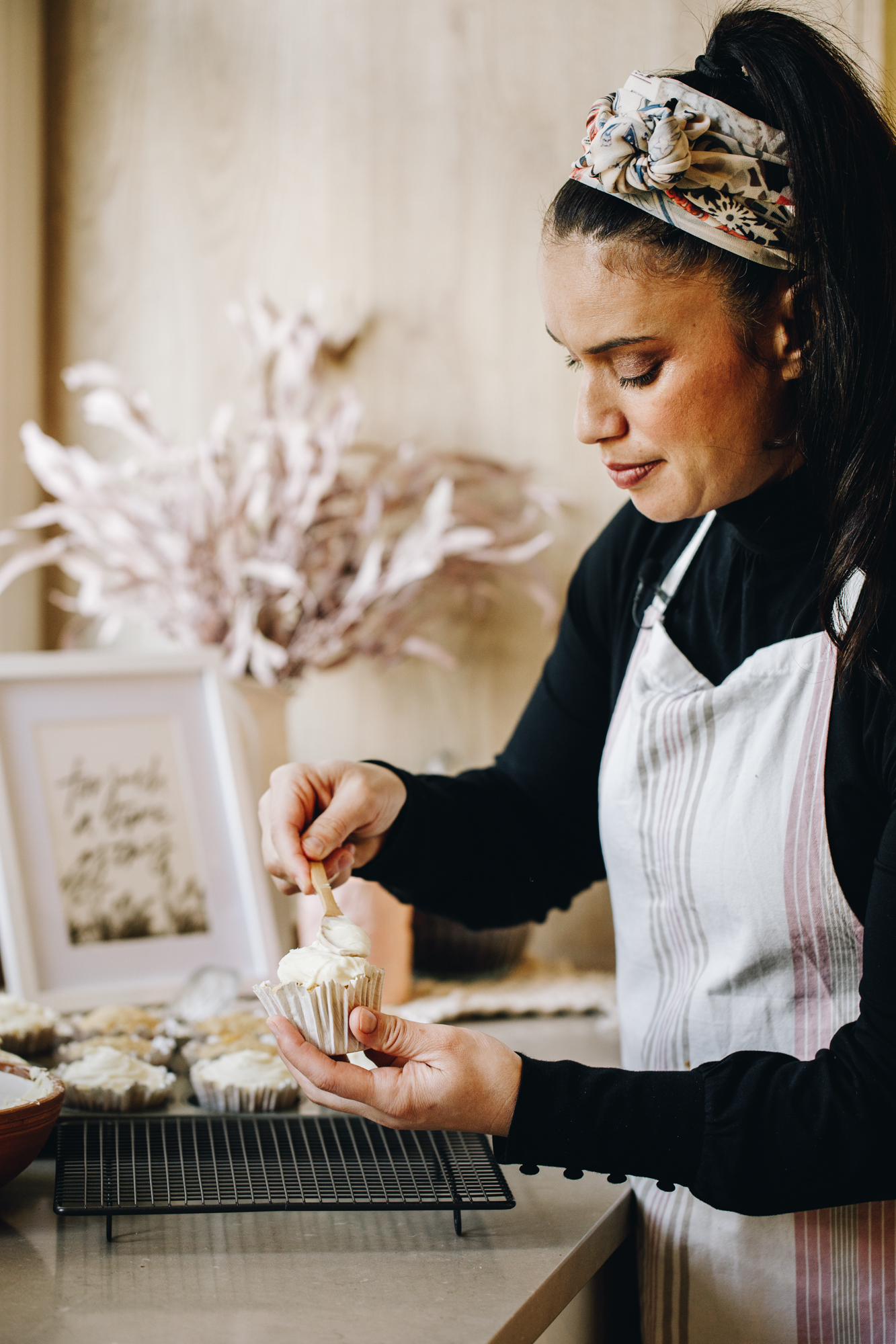 Naomi Toilalo spreading cream cheese frosting on hummingbird muffins.
