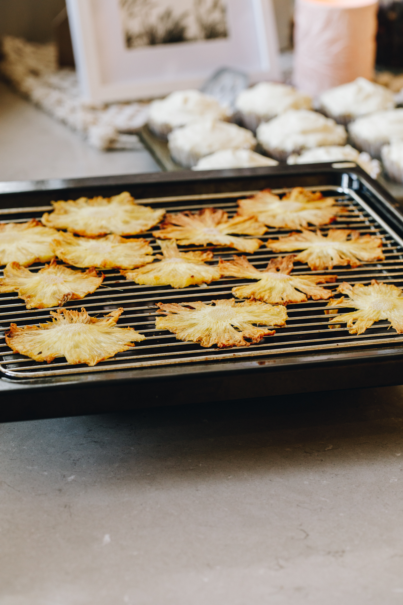 Dried pineapple on top of a cooling rack inside a baking tray.