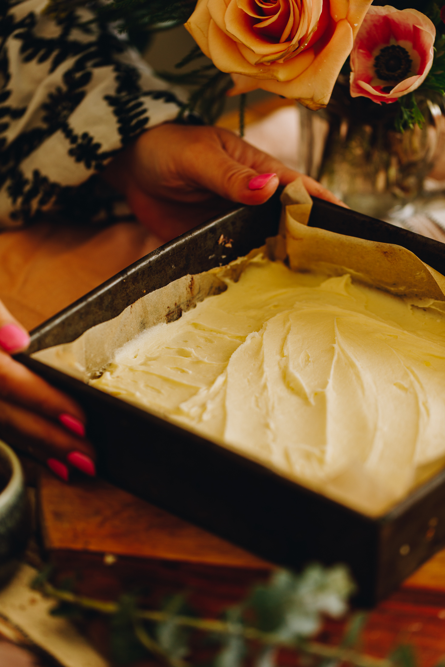 A vintage tin with cream cheese peppermint filling spread on a wooden board with flowers in the background.