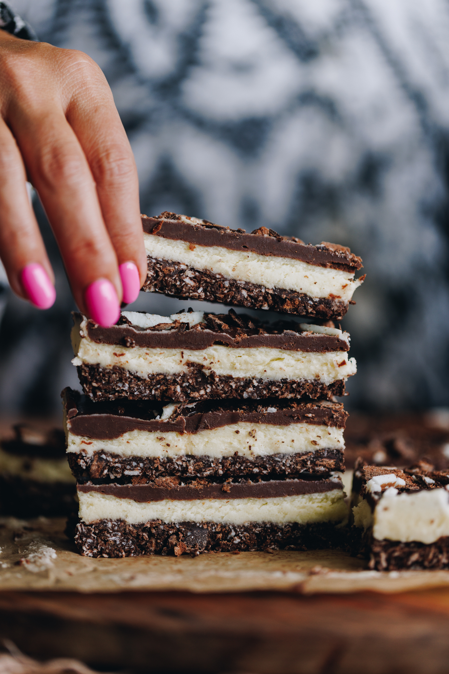 Three no-bake mint slices stacked as another one is being placed on top.