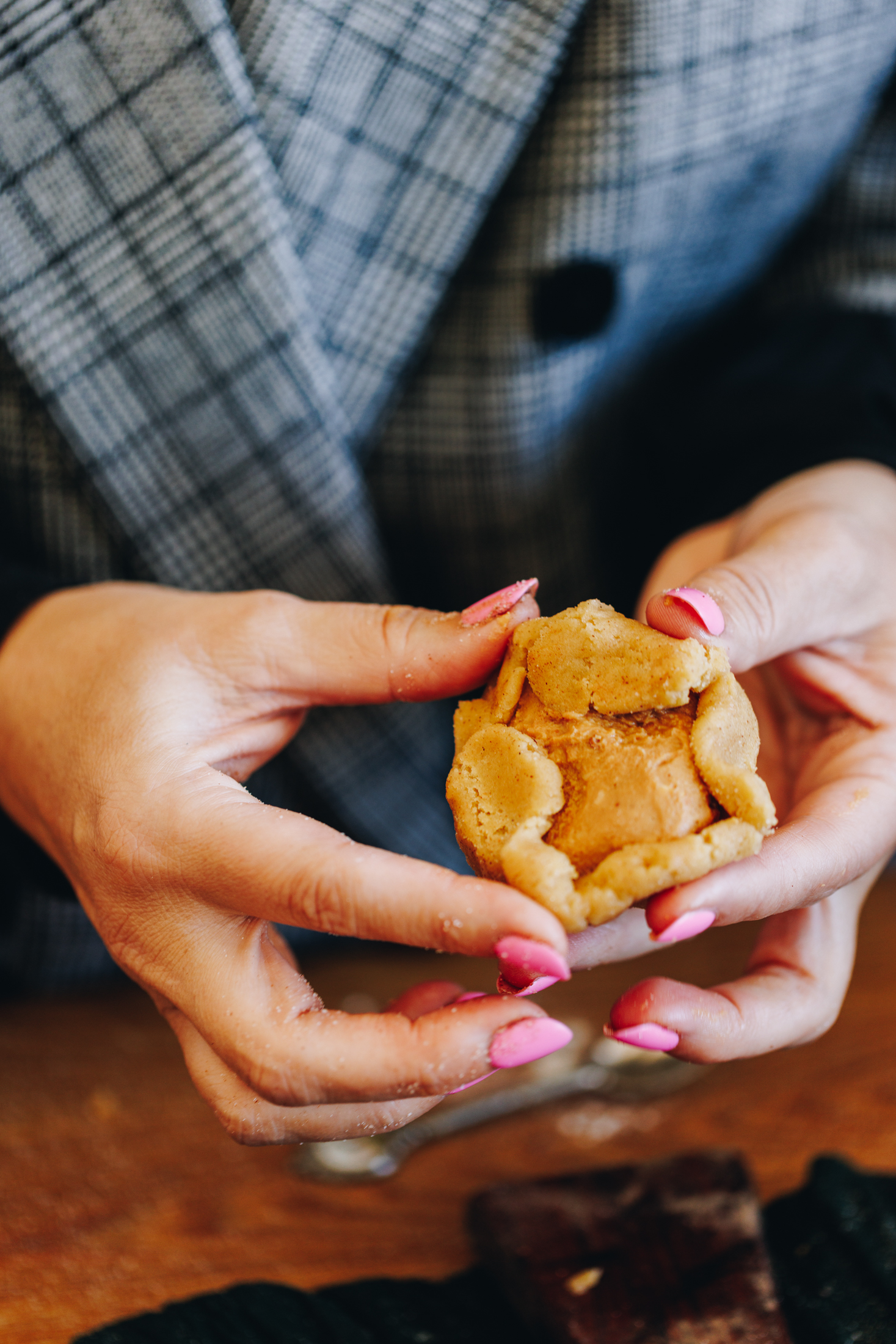 Hands stuffing peanut butter into cookie dough. 